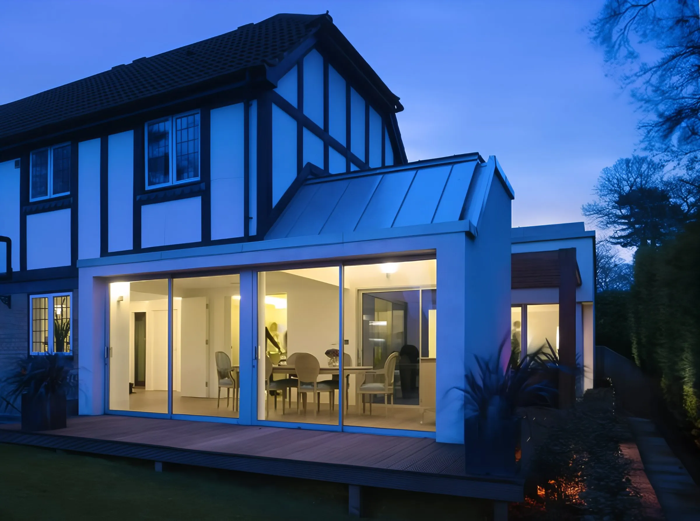 Rear extension of the 1990s house at dusk, lit from inside