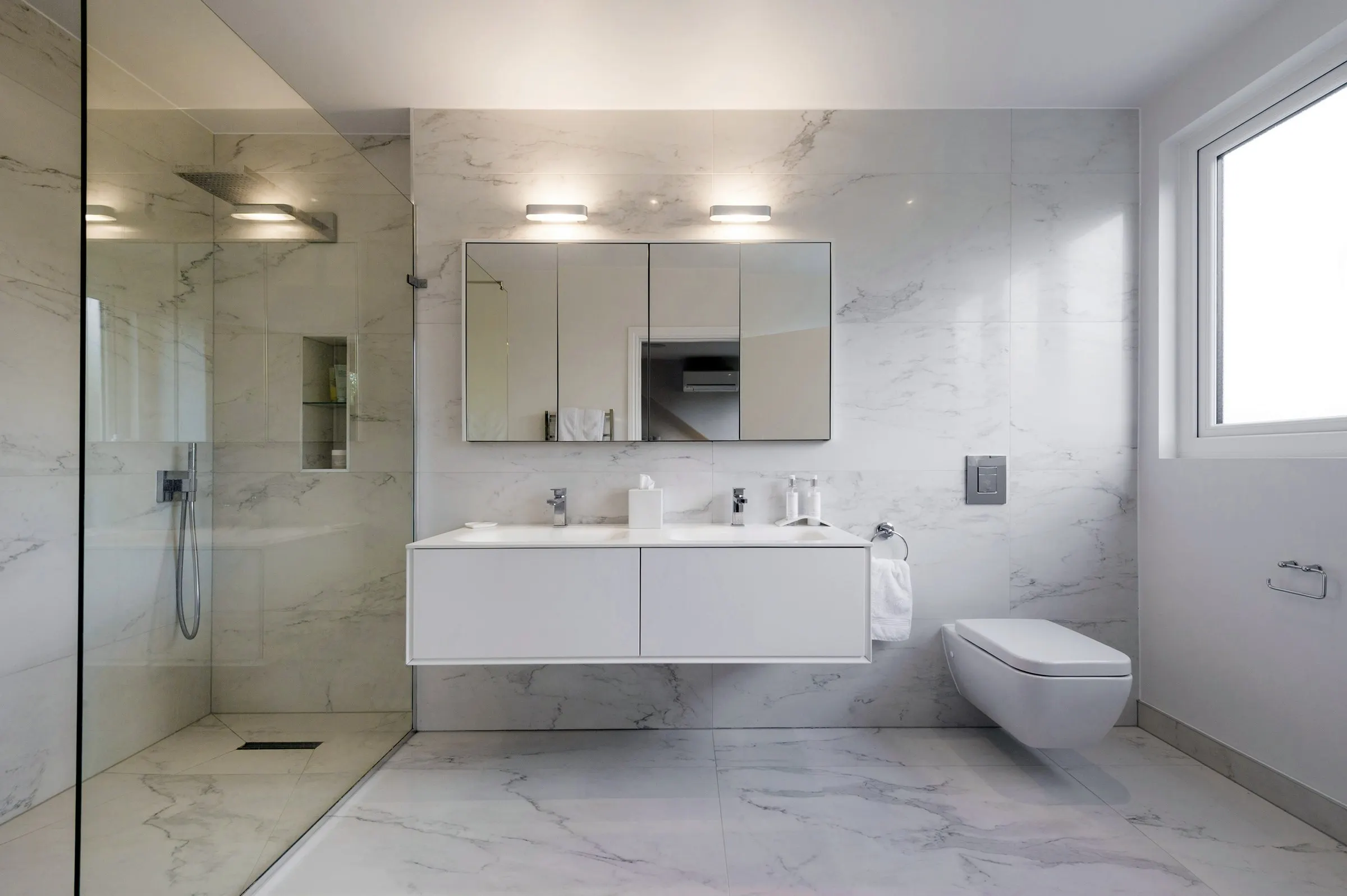 Marble-tiled bathroom with walk-in shower and floating vanity
